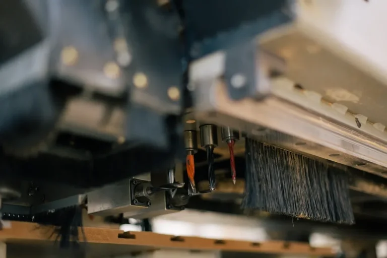 CNC router head with spindle bits and dust brush over a wood workpiece