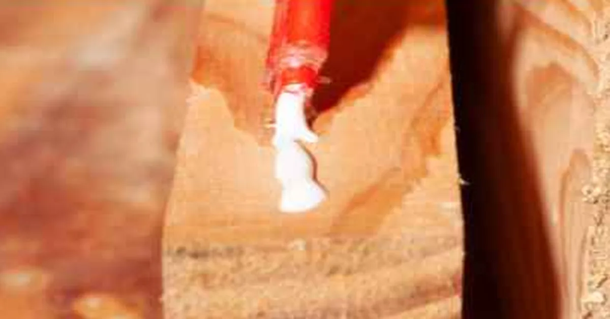 Hot glue gun applying glue to a wood board