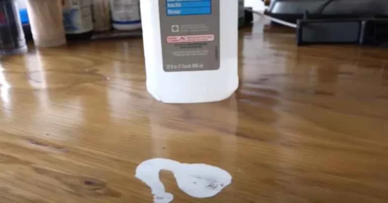clear rubbing alcohol bottle spilled next to a pale white mark forming on a wood tabletop