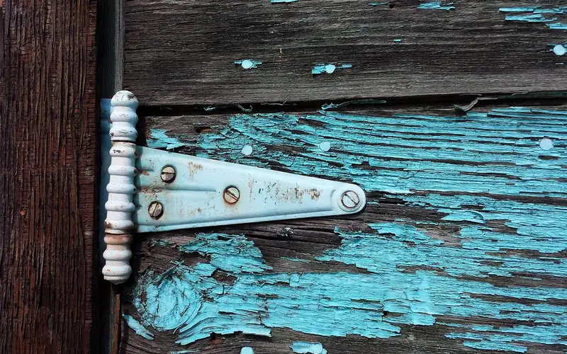 Old wood door and hinge with cracked, peeling blue paint Old wood door and hinge with cracked, peeling blue paint