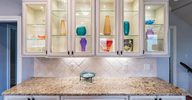 White painted kitchen cabinets with glass-front upper doors over a granite counter
