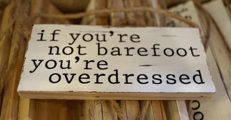 Black lettering on a whitewashed wooden sign