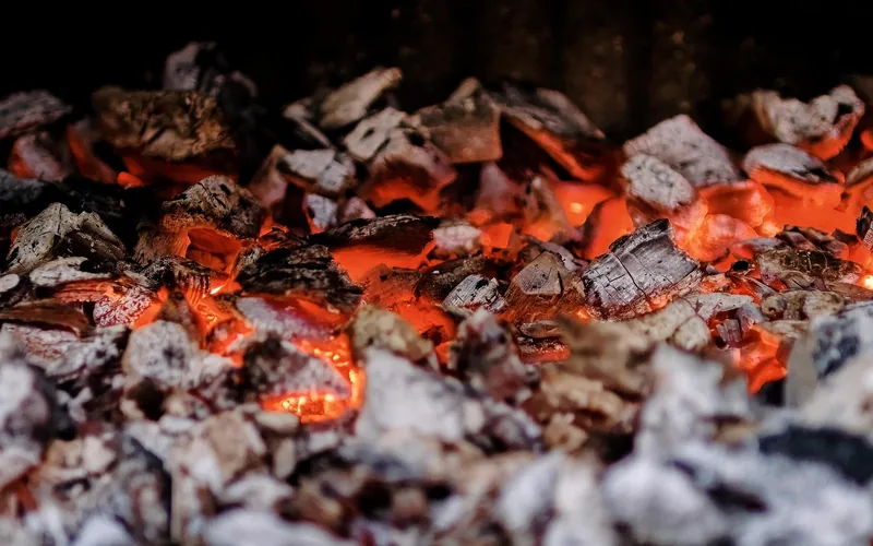 glowing wood embers forming gray ash in a fireplace