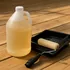 Jug of clear wood waterproofing sealer with a paint roller tray