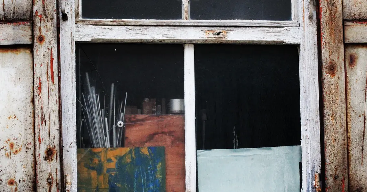 Rotted wooden door frame with peeling paint showing wood rot decay