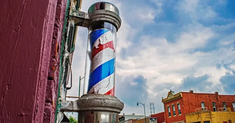 Vintage barber pole with red, white and blue spiral stripes mounted on a brick storefront