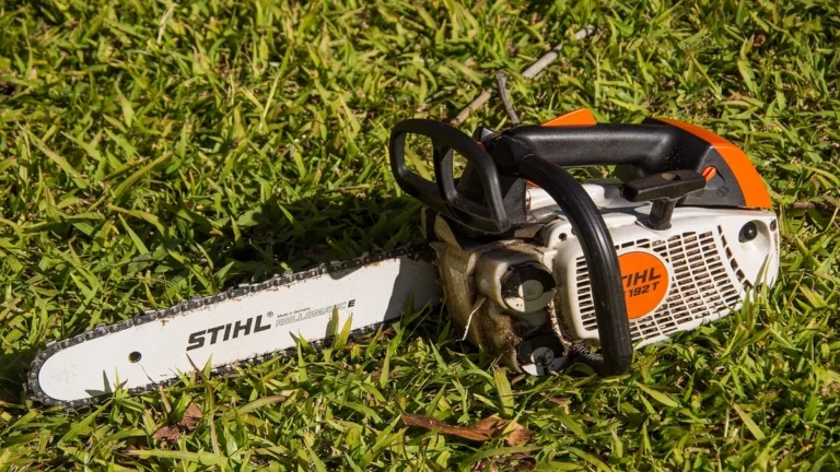 Chainsaw with guide bar resting on grass, showing full bar length from tip to powerhead