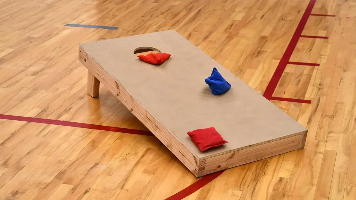 Cornhole board with bean bags on a gym floor