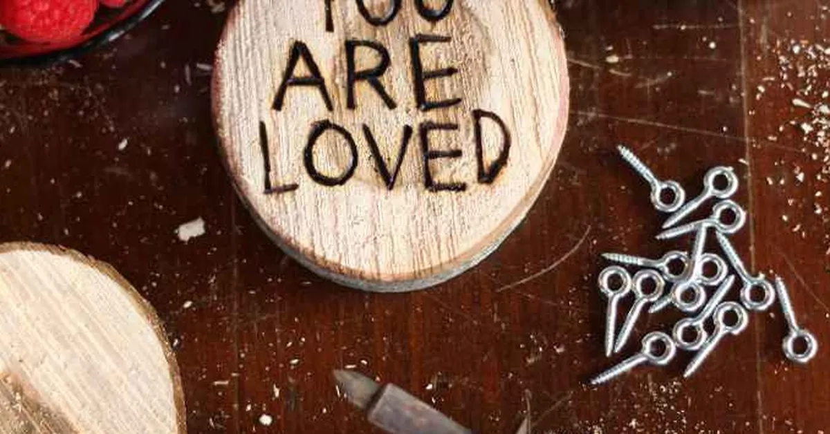 Wood burning pyrography design reading You Are Loved burned into a wood slice