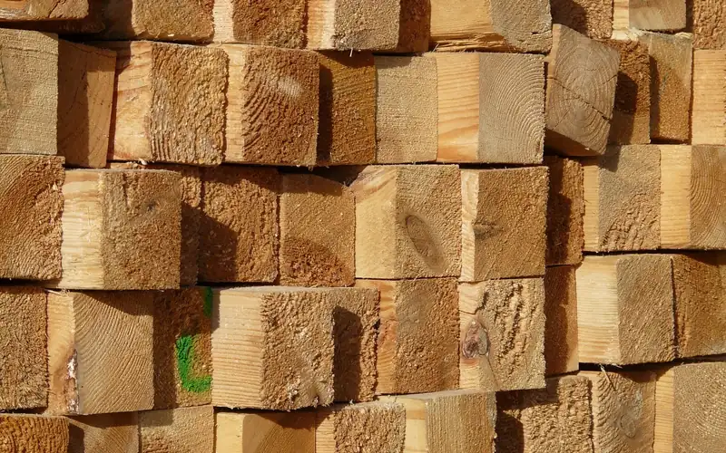 Lumber ends stacked and stickered at a yard, showing airflow between boards to prevent moisture-driven warp