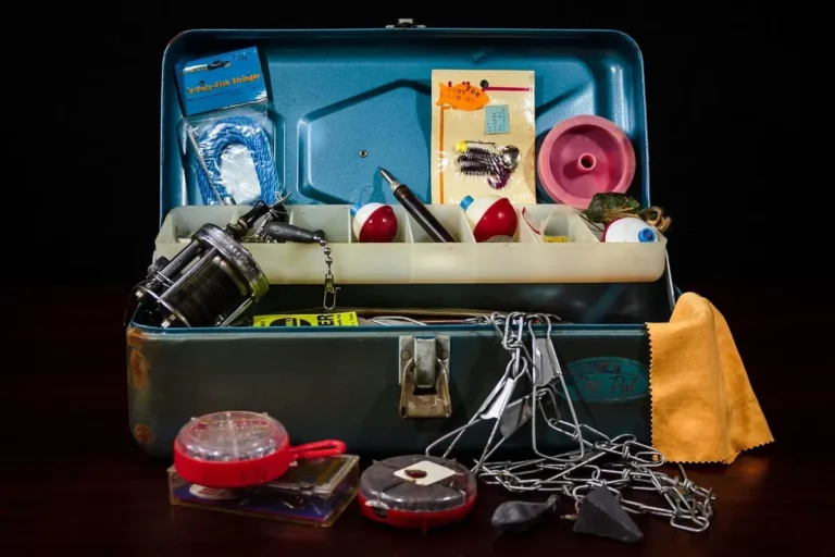 Open fishing tackle box with a lift-out tray, reel and lures