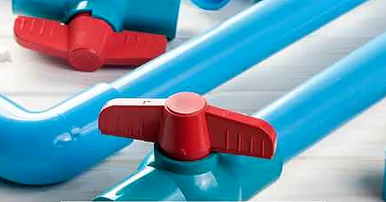 Blue PVC pipe fittings and shutoff valves laid on a wood-plank surface