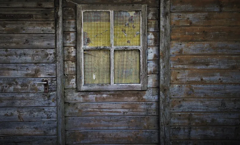 Old weathered wooden wall with horizontal board siding around a window Old weathered wooden wall with horizontal board siding around a window