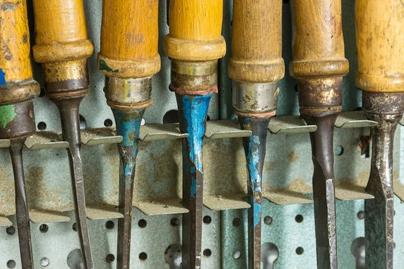 A set of wood chisels of different widths stored on a workshop rack