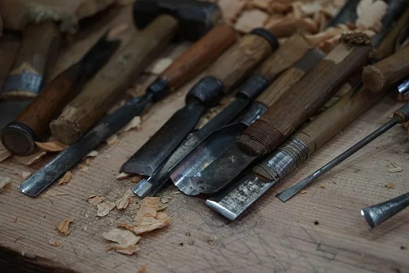 Several wood chisels with visible bevel edges laid out on a workbench with shavings