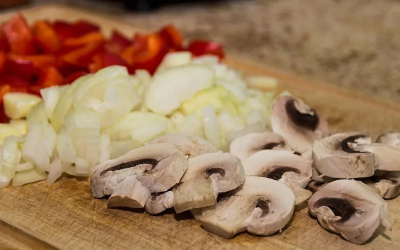 Wood cutting board with fine knife scratches next to sliced vegetables