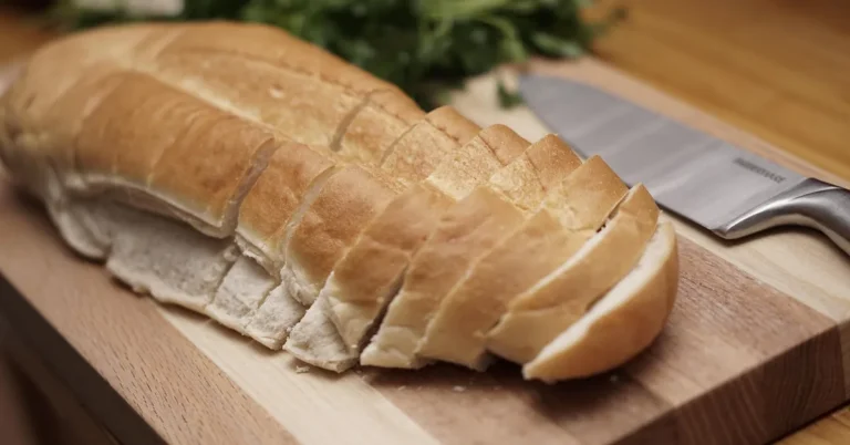 Sliced bread on a wood cutting board next to a chef knife