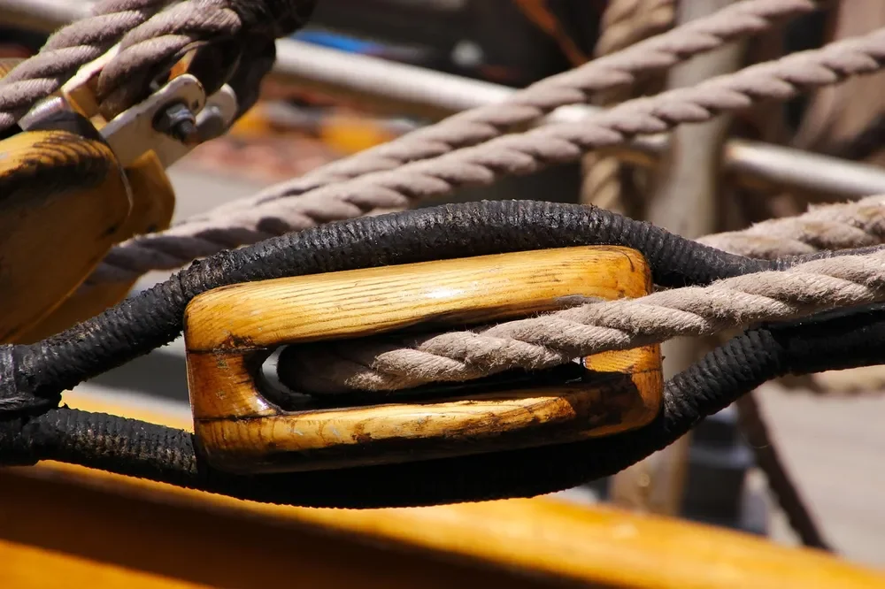 Wooden pulley block with natural fiber rope running through the sheave
