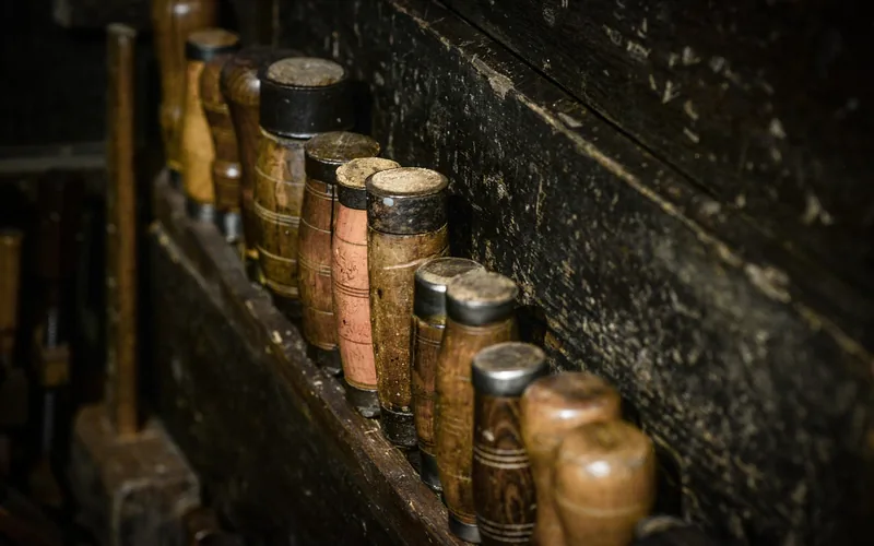 A row of wood chisels and carving tools stored on a workshop bench shelf