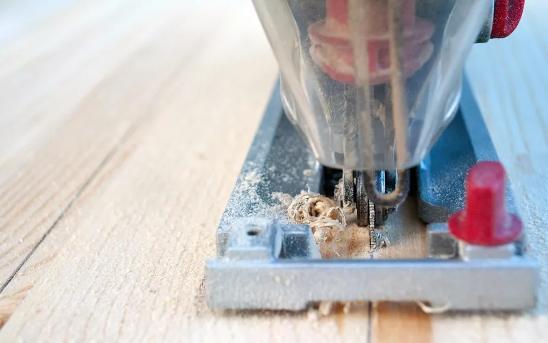 jigsaw cutting through a damaged deck board close up with sawdust on the blade jigsaw cutting through a damaged deck board close up with sawdust on the blade