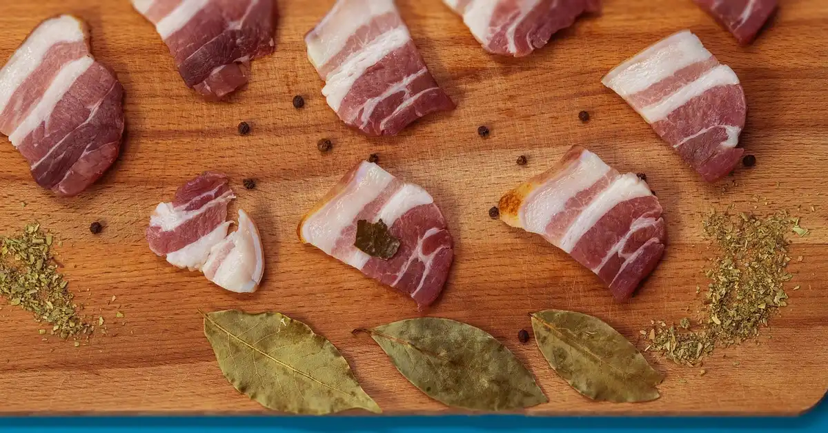 Raw meat sliced on a wood cutting board with spices, showing safe meat prep on wood