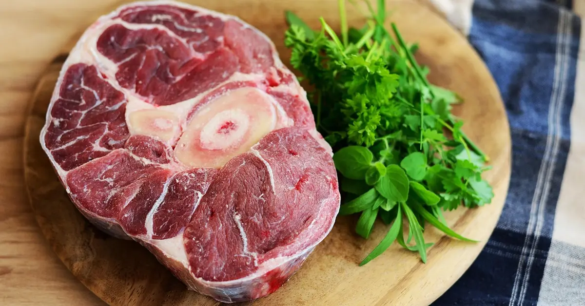 Raw meat resting on a wood cutting board before cleaning and sanitizing