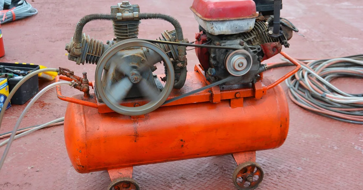 gas-powered air compressor with visible tank, pump, and drive belt in a workshop