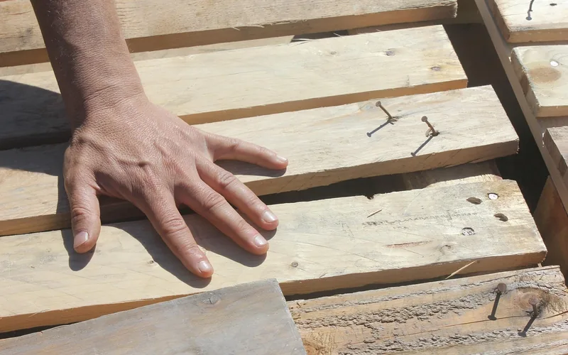 Hand checking the fit and spacing of raw wood planks before installing them on a wall Hand checking the fit and spacing of raw wood planks before installing them on a wall