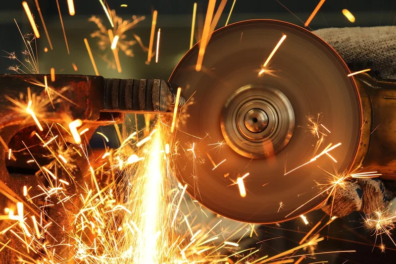 Abrasive cut-off wheel cutting a steel bar clamped in a vise with sparks flying Abrasive cut-off wheel cutting a steel bar clamped in a vise with sparks flying