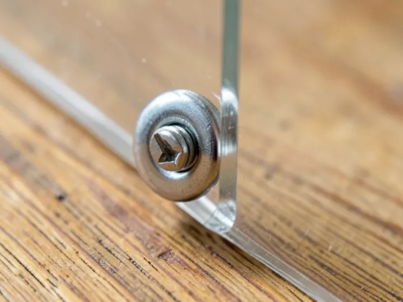 Stainless steel standoff screw holding an acrylic panel a gap away from a wood surface