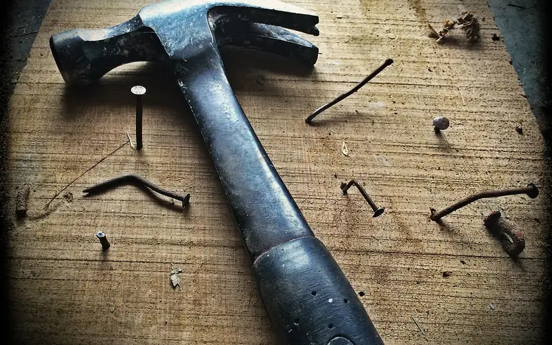 hammer and nails on a wood board representing structural connector hardware