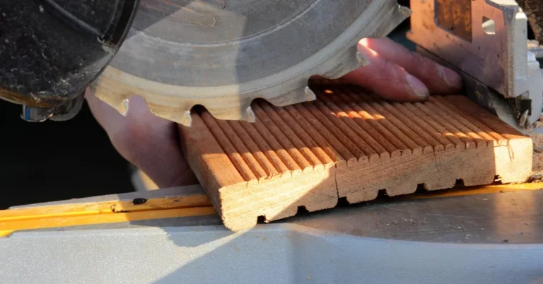 Compound miter saw blade cutting through a grooved deck board close up