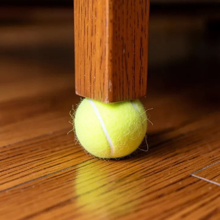 tennis ball used as a DIY furniture glide on a chair leg