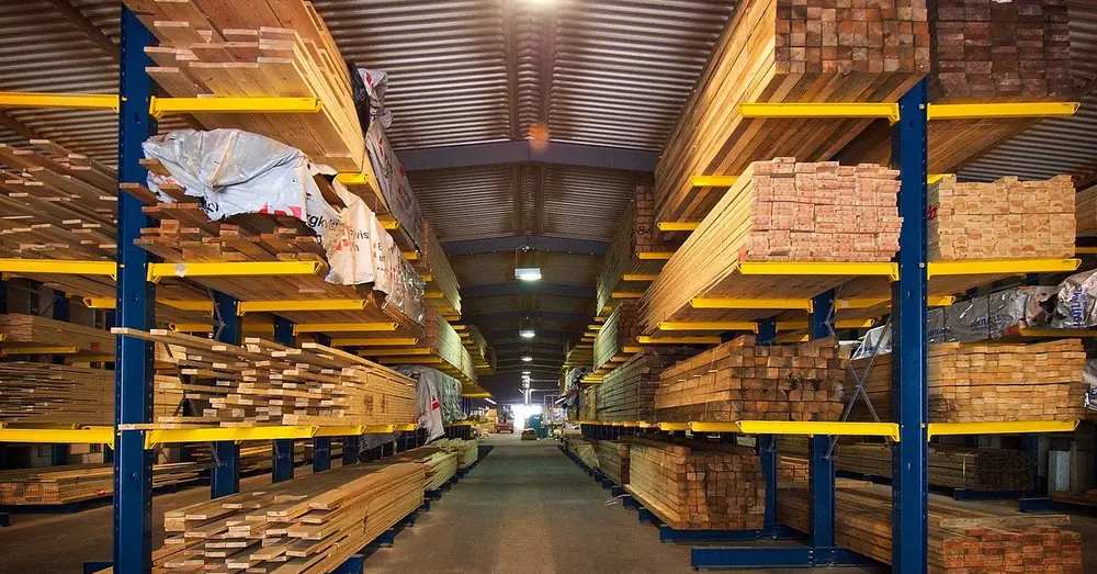 Warehouse aisle with racks of stacked lumber at a building supply store