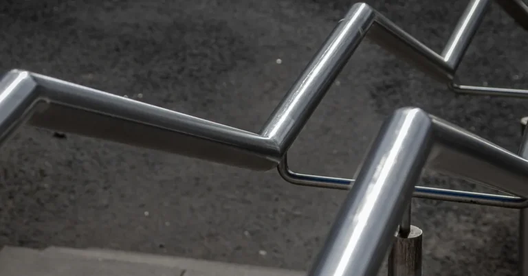 Close-up of a polished stainless steel railing with angled handrail sections outdoors