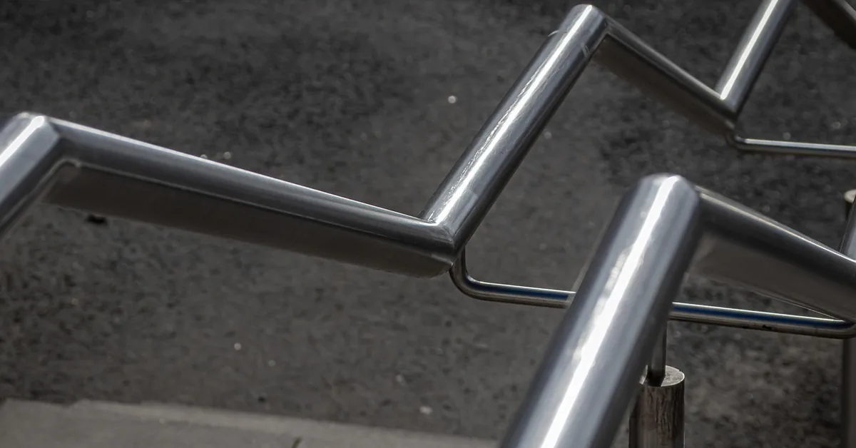 Close-up of a polished stainless steel railing with angled handrail sections outdoors