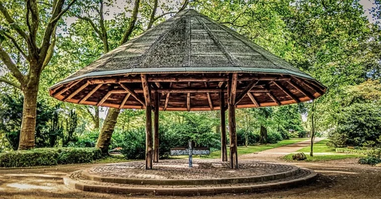 Wooden gazebo with hardtop roof set up in a backyard garden