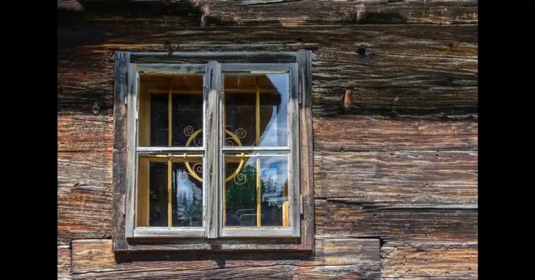 Close-up of a custom wooden window frame set into a wood wall, illustrating wood window construction and cost factors