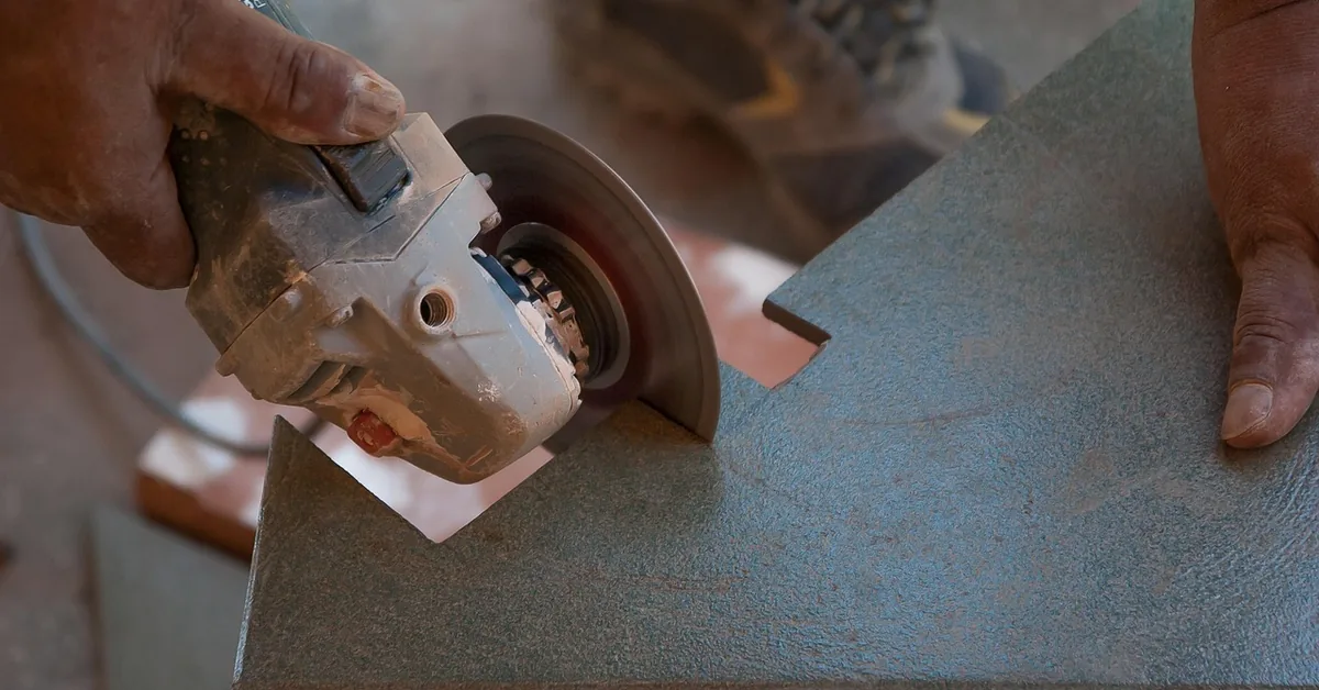 Tile installer cutting a porcelain wood-look plank tile to size with an angle grinder before installation