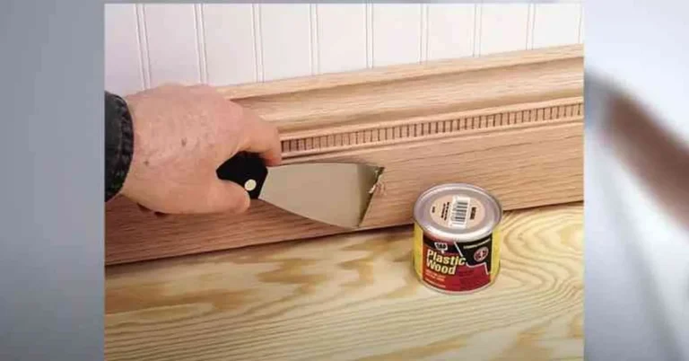 hand using a putty knife to press wood filler into trim before staining