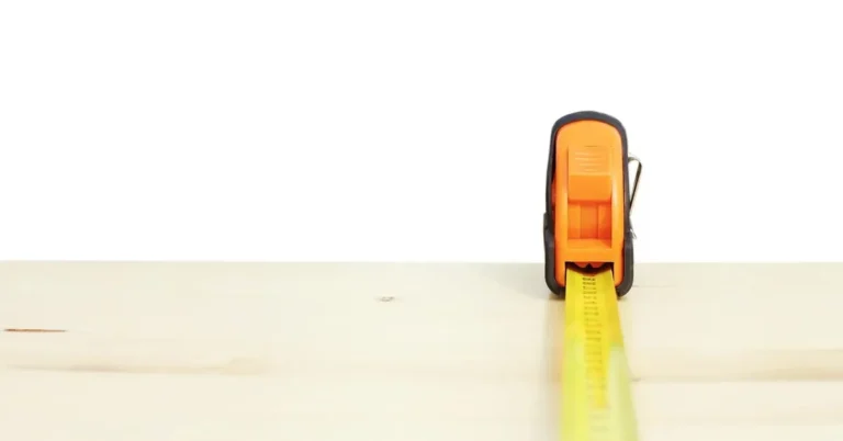 Tape measure laid along pine boards to measure board coverage