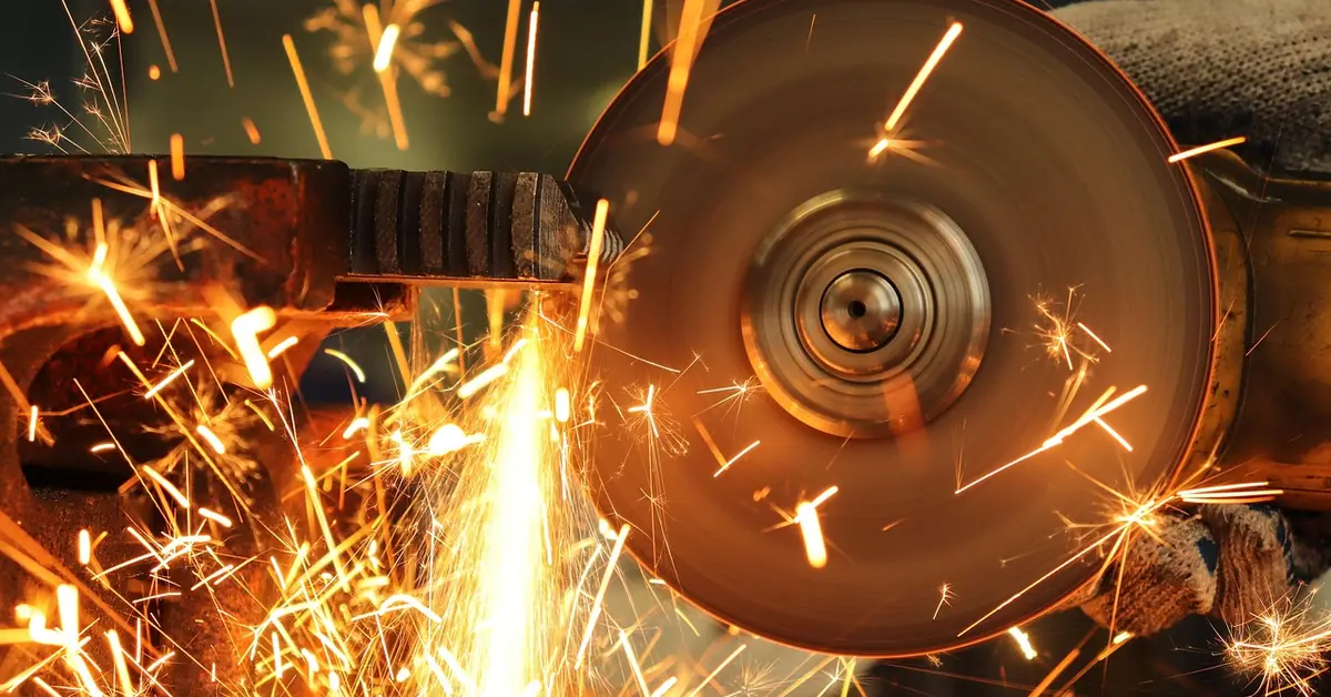 Abrasive cut-off wheel throwing sparks while cutting steel clamped in a vise