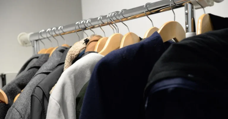 Real wooden coat hangers with contoured shoulders holding jackets and coats on a closet rail