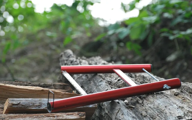 Red bow saw frame resting on a log
