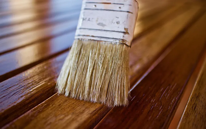 Brush applying a thin coat of finish to wooden furniture slats Brush applying a thin coat of finish to wooden furniture slats
