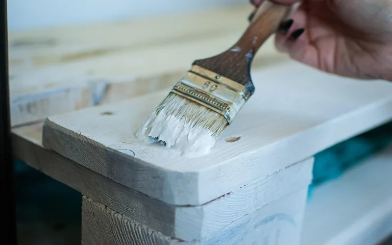 hand brushing finish evenly onto a raw pine board edge
