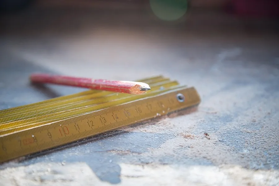 carpenter measuring a board, an early planning step that affects total project time