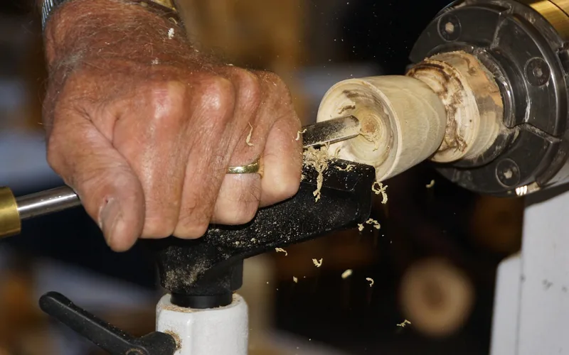 chisel guided against a spinning wood spindle close-up of a hand guiding a chisel against a spinning wood spindle on a lathe