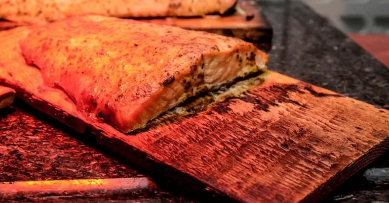 Salmon grilling on a charred cedar plank showing wear from reuse