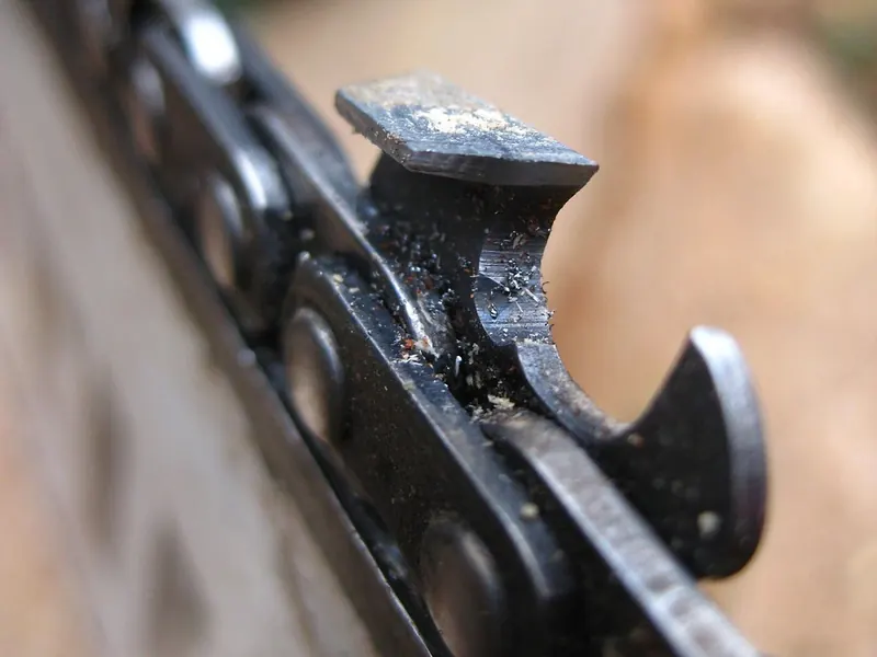 Close-up of a saw chain cutter and the depth gauge ahead of it